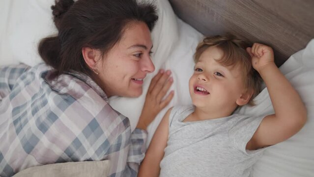 Family moment between mother and child in morning bed showing love and affection waking up