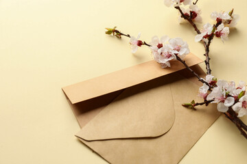 Beautiful blooming spring branch and envelopes on light color background