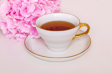 Cup of tea and pink hydrangea on white table