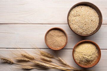 Three kind of bran in bowl on a white wooden table.