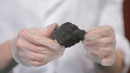 Male hands in gloves holding coal. Scientist with a sample of coal. Black coal in miner's hand