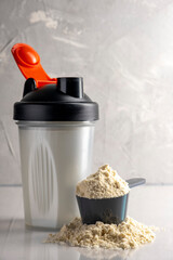 Shaker and protein powder on grey background. Sports nutrition concept.