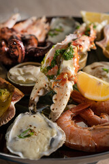 Baked oysters, crab with sauce and a slice of lemon. A glass of white wine with a seafood platter