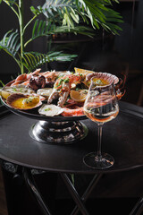 Baked oysters, crab with sauce and a slice of lemon. A glass of white wine with a seafood platter