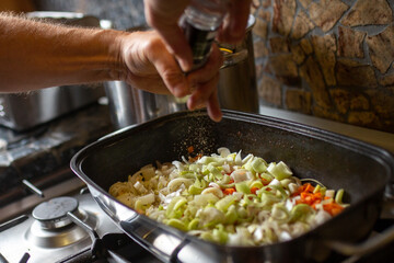 Mann Koch würzt Soße für mehrere Personen beim Kochen