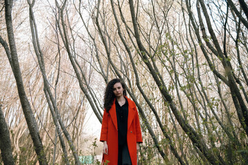 portrait of curly brunette woman in red coat in the park