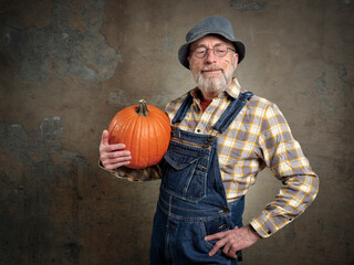 portrait of a happy and smiling  senior, bearded man with a pumpkin from his garden, gardening...