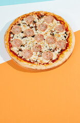 Italian pizza with ham and mushrooms on coloured background. Ham pizza in minimal style on orange and blue colours. American pizza delivery concept color backdrop