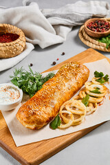 Meat pie with greens and onion on wood plate. Eastern food - beef pie with sesame. Eastern pastry with Minced meat.