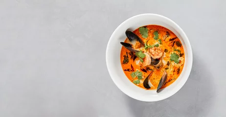 Fotobehang Traditional asian food - tom yam kung with prawn and mussels. Tom yum soup with seafood and coconut milk. Tom yam in ceramic bowl on gray stone background. Oriental cuisine. Asian menu. © Ryzhkov