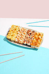 Set of hot maki rolls on coloured background. Baked sushi roll assortment on ceramic plate. Maki sushi in minimal style. Japanese menu concept.