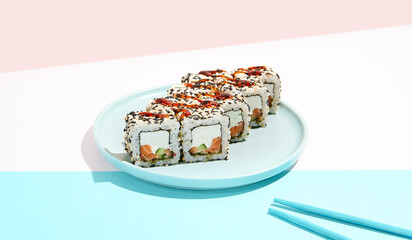 California maki roll with sesame on coloured background. Sushi roll with salmon and cheese inside,sesame outside. Green Maki sushi in minimal style. Japanese menu concept.