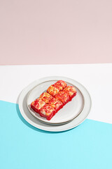 Baked Maki roll with tobiko caviar on ceramic plate. Hot sushi roll with tobiko and cheese topped on coloured background. Japanese menu concept. Hot maki sushi in modern style.