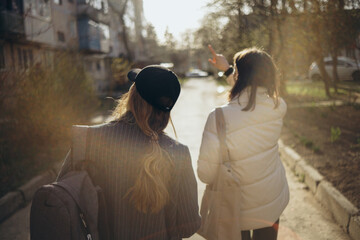 Back view portrait of two women walking and talking in a park asunny day