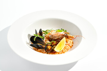 Italian dish - seafood risotto on white plate. Risotto frutti di mare with shrimp, mussels and squid. Seafood in marinara sauce with arborio rice. Paella with prawn and mussels. Seafood menu.