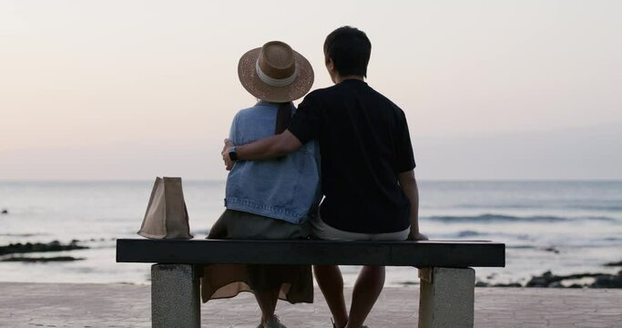 Couple sit on the bench and look at the sea