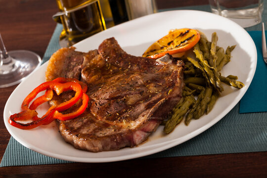 Appetizing beef steak served with grilled orange and bell pepper and boiled asparagus