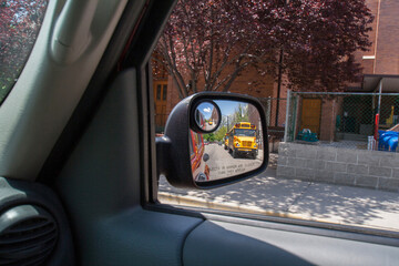 School bus in a side mirror of a car