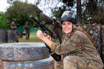 Fototapeta premium Paintball players of one team in camouflages and masks aiming with gun in shootout playing field