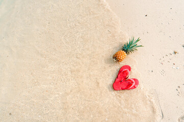 Fototapeta na wymiar Summer beach vacation with pineapples and flip flops on the beach