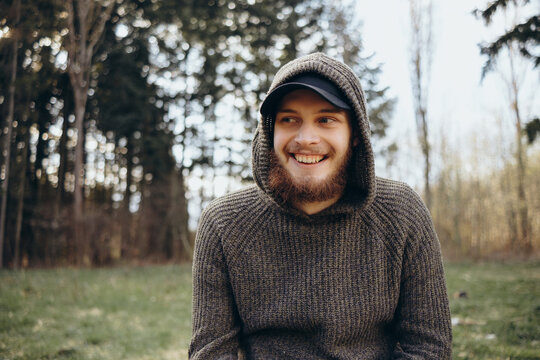 Happy man in a hood seating in the park after smoking weed