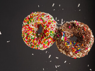 Sweet donuts on a gray background in a frozen flight. Sweet food, children's favorite treat, youth culture. Birthday, holiday. Shop, cafe, restaurant, hotel. There are no people in the photo.