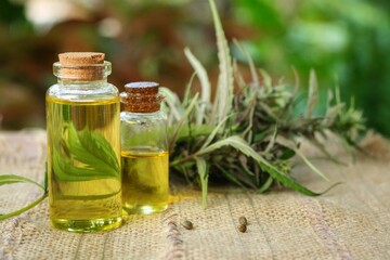 Glass bottles of extraction hemp medicine,cbd oil,hemp oil and cannabis leave on the wooden table with blurred nature background.Medical hemp products for medical use.Herb and medical concept.