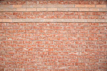 An image of a textured red brick background wall on the side of an architecture building. 