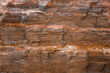 An image of a real orange and red  grunge rock wall texture with chips, cracks, and scrapes. 