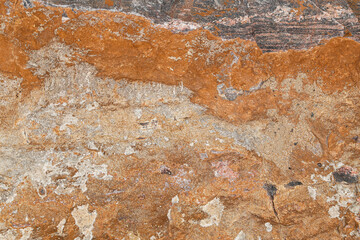 An image of a real rock wall texture with orange and red color and layers of grungy, cracked...