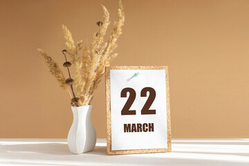 march 22. 22th day of month, calendar date.White vase with dried flowers on desktop in rays of sunlight on white-beige background. Concept of day of year, time planner, spring month