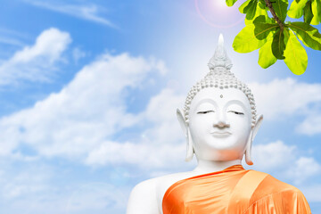White buddha statue over blurred sky background, faith and religion concept