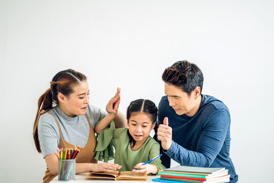 Portrait enjoy happy love asian family father and mother with little asian girl learn and study.Mom and dad with asian young girl writing with book make homework in homeschool at home.Education