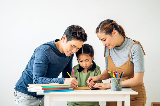 Portrait enjoy happy love asian family father and mother with little asian girl learn and study.Mom and dad with asian young girl writing with book make homework in homeschool at home.Education