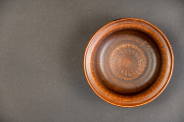 An empty clay bowl against a black background. Brown new fired clay dishes. Selective focus.