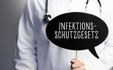 Infektionsschutzgesetz (IfSG). Arzt mit Stethoskop hält Sprechblase in Hand. Text steht im Schild....