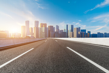 Empty asphalt road and modern city skyline with buildings in Hangzhou at sunset, China.