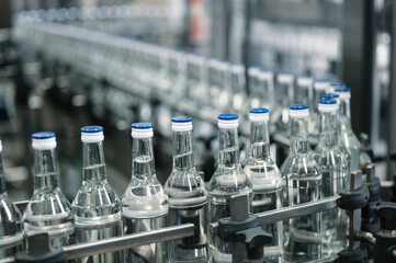 Closed glass bottles of upscale vodka transported by line