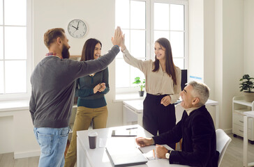 Obraz premium Overjoyed businesspeople give high five celebrate shared business success or goal achievement in office. Smiling colleagues or coworkers engaged in teambuilding activity at work. Teamwork concept.