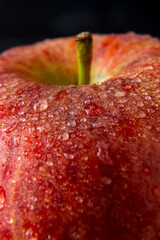 Red delicious apple macro photo with water drops, dark moody photo. Abstract fruit background