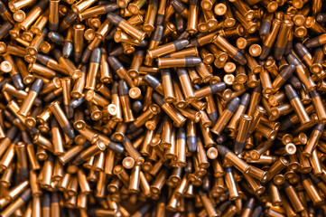 Heap of black and golden small-caliber bullets on table