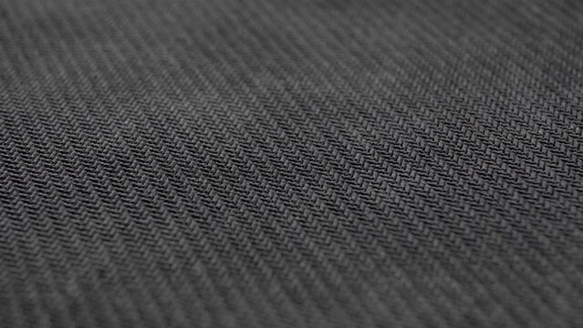 Black textile grunge woven material. Dark dusty textured fabric close up. Woven structure. Macro. Rotation