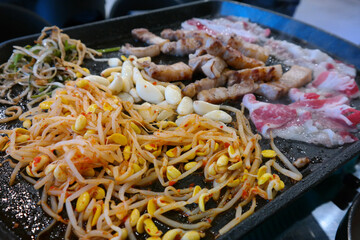 Thick pork belly is grilled with various vegetables on the fire.