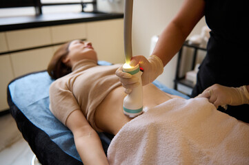 Beautiful woman receiving hardware spa procedure for cellulite reduction and weight loss in medical clinic