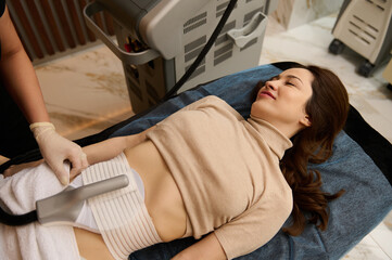 Charming brunette receiving lipo laser therapy, anti-cellulite treatment in medical spa