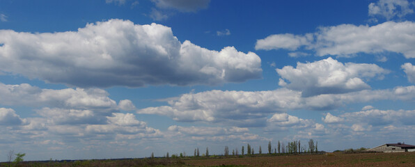 Panoramic landscape with blue sky and white and gray clouds.