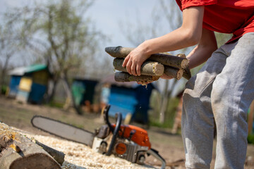 teenager helps his parents to stack firewood for the heating season