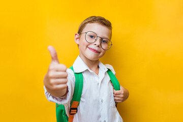 Young school boy showing ok isolated on yellow background. Positive kid looking to camera with confident. Stylish child go back to school