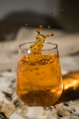 Glass with orange drink on sandy beach
