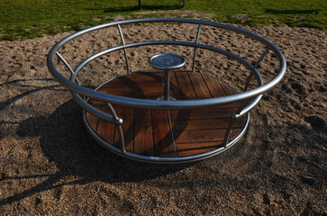 metal carousel with a wooden floor on the playground serves children for the development of motor...